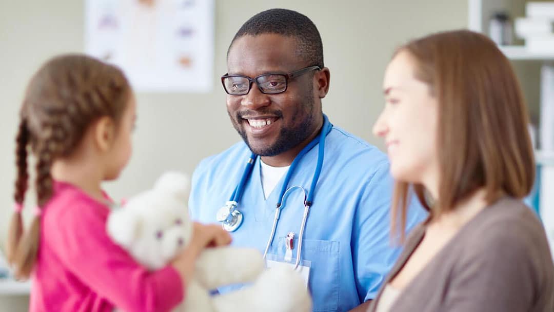 Male nurse consulting child with a teddy bear and her mother