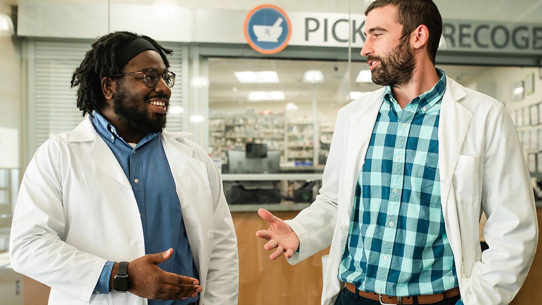 Two male pharmacists speaking with each other