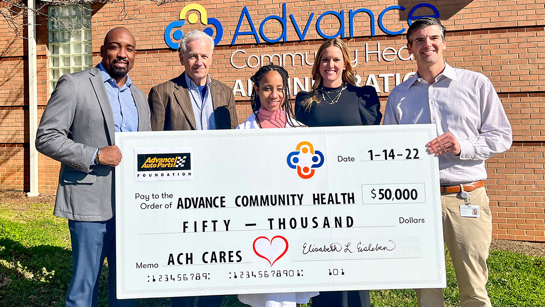 Employees from Advance Community Health and Advance Auto Parts holding a large grant check